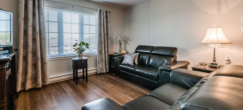 Suite living room with leather sofas beside tall windows.