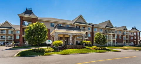 Residence building with balconies, a stone entrance and landscaping.