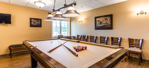 Billiards room with a pool table and wooden chairs.