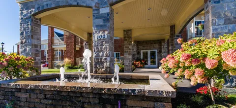 Covered entrance with a fountain and flowering planters.