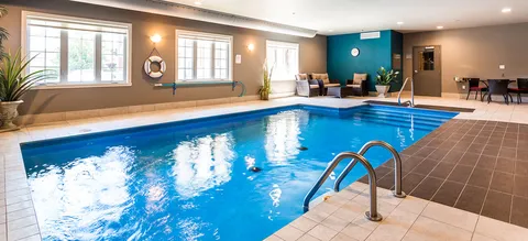 Indoor pool with tiled flooring and seating beside windows.