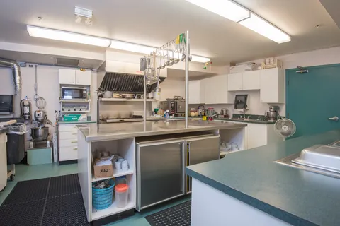 Commercial kitchen with stainless counters and cooking equipment.