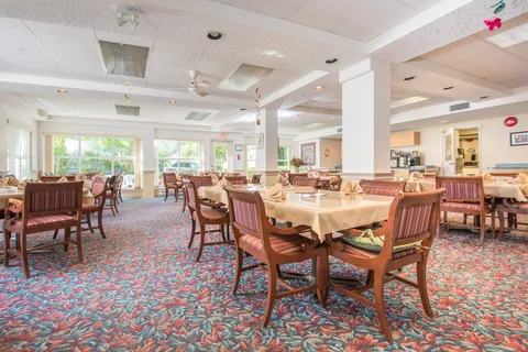 Dining room with set tables, chairs and broad windows.
