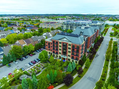 Aerial view of a brick residence building beside a parking lot and trees