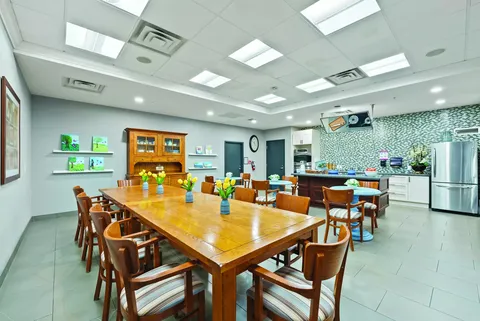 Long wooden dining table with chairs beside a kitchen counter