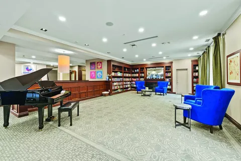 Room with a grand piano, blue armchairs and bookshelves