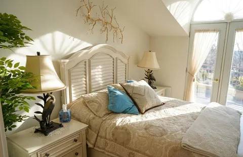 Bedroom with a white headboard, bedside lamps and a large window
