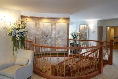 Armchair beside a curved stair railing, flowers and abstract wall art