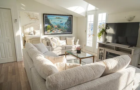 Sitting area with white sofas, a glass coffee table and a television