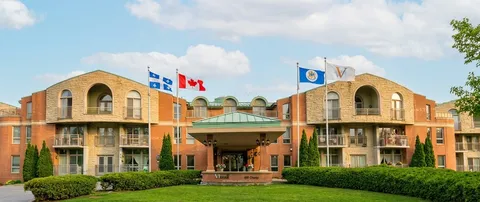 Front of a brick residence with balconies, flags and a covered entrance