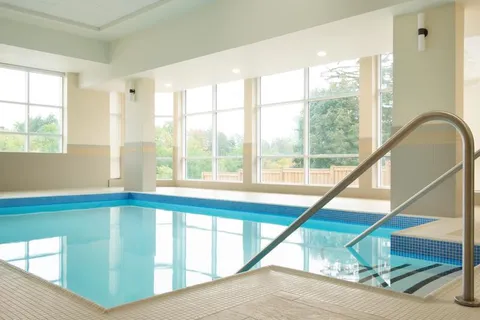 Indoor pool with steps, a metal handrail and large windows