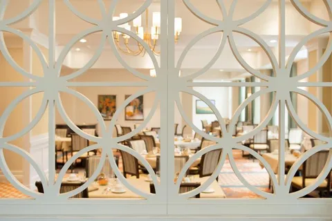 Dining tables and chairs seen through a decorative white partition