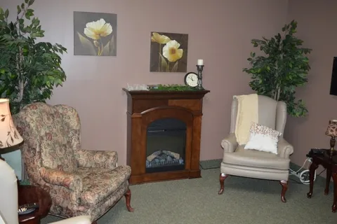 Armchairs beside a fireplace with flower paintings above