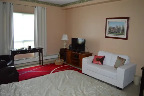 Bedroom with a bed, white sofa and a dark television