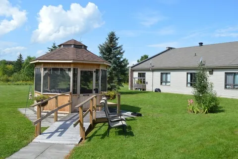 Wooden gazebo beside a lawn and the residence building