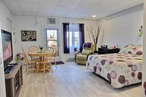 Suite with a bed, dining table and chairs beside patio doors.