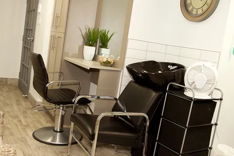 Salon with black chairs and a hair-washing basin.