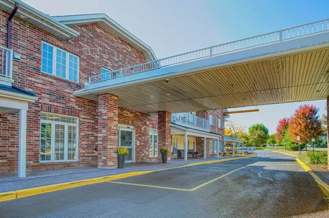 Brick residence and wide entrance canopy beside a driveway.