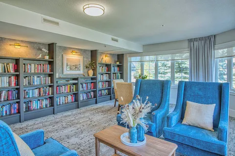 Library with shelves of books and blue lounge chairs.