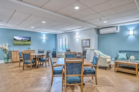 Activity room with tables, chairs and wall television.