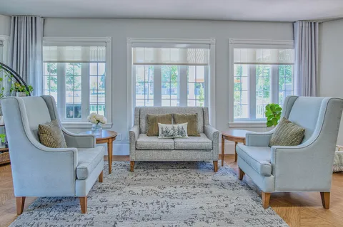 Sitting area with a sofa, armchairs and bay windows.