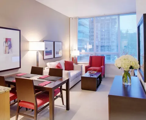 Sitting and dining area with a sofa, red armchair and table