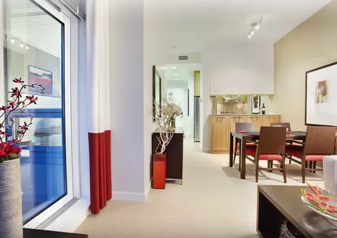Dining table beside a kitchenette and a large window