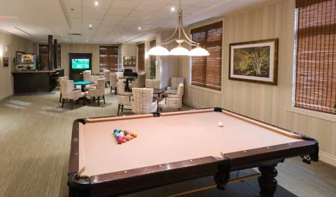 Billiards table beside wicker chairs and small round tables