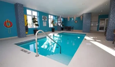 Indoor swimming pool with a handrail, large windows and blue walls