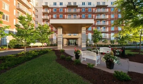 Garden path and white benches facing a brick building entrance