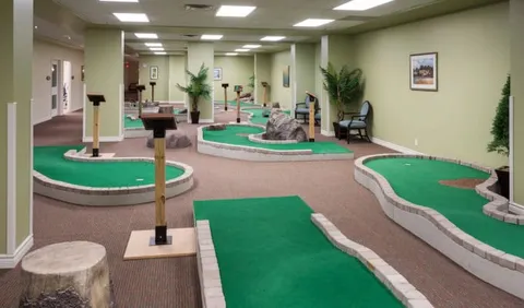 Indoor miniature golf course with green putting surfaces and obstacles