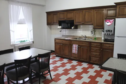 Shared recreation room with tables, chairs and a kitchenette.