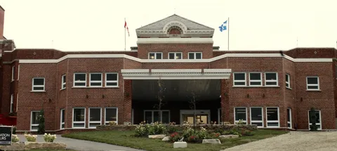 Brick front facade with a covered entrance and planted beds.