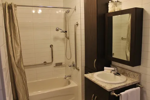 Suite bathroom with a bathtub, shower, grab bars and sink vanity.