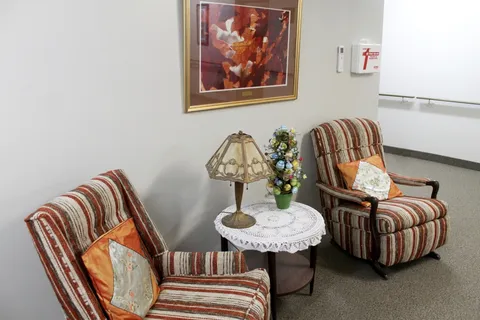Shared sitting area with two striped armchairs and a lamp table.