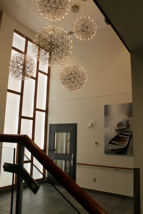 Entrance stairwell with tall windows, glass railings and globe pendant lights.