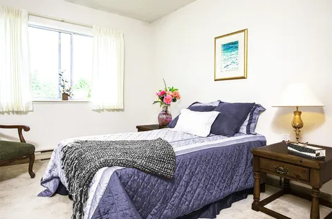Bedroom with a bed, bedside table, lamp and framed seascape