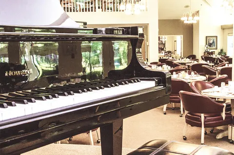 Grand piano with dining tables and chairs behind it
