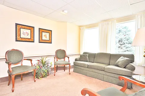 Room with a sofa, armchairs, framed floral pictures and a window