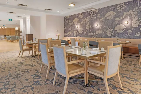 Dining room with wooden chairs, set tables and floral wallpaper.