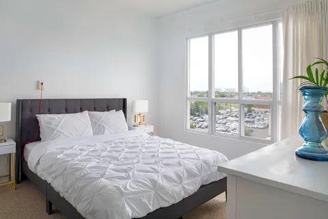 Bedroom with a double bed, a dresser and a large window.