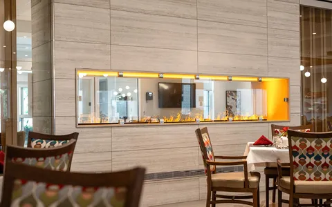 Dining area with upholstered chairs beside a fireplace