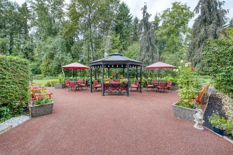 Garden patio with a gazebo, red umbrellas and seating