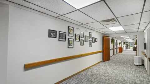 Carpeted hallway with wooden handrails and framed flower pictures
