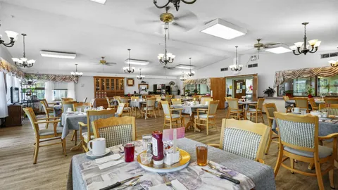Dining room with set tables, wooden chairs, chandeliers and ceiling fans