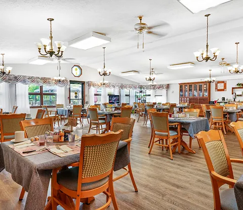 Dining room with wooden tables and chairs, curtained windows and chandeliers