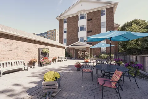 Rear of the residence beside a paved courtyard with tables and umbrellas.