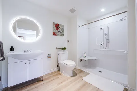 Bathroom with a vanity, illuminated mirror, toilet and shower.
