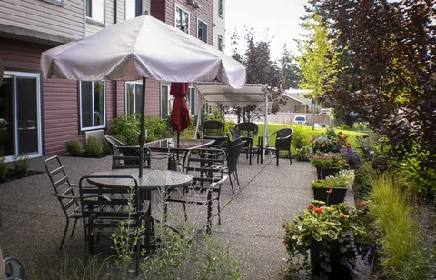 Outdoor patio with tables, chairs, umbrellas and planted borders