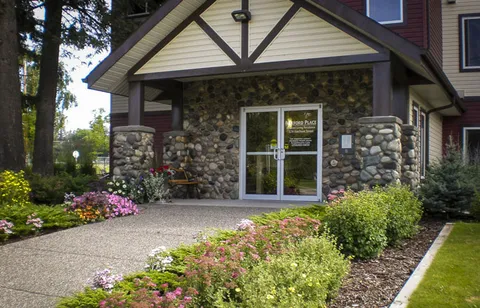 Covered glass entrance with stone walls and flower beds